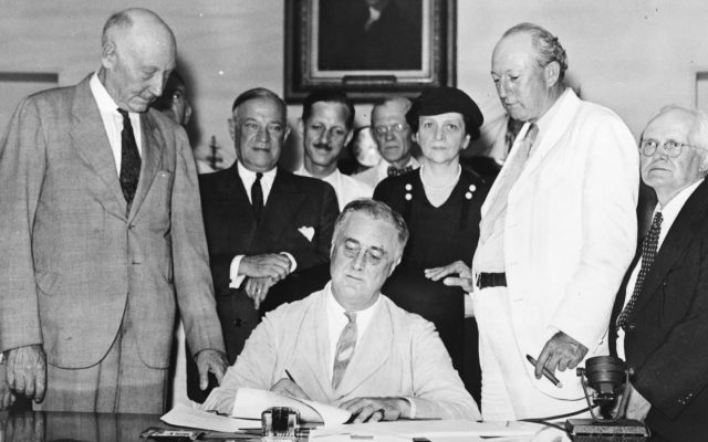 President Franklin Roosevelt signs the Social Security Act in 1935 as members of Congress and Labor Secretary Frances Perkins look on
